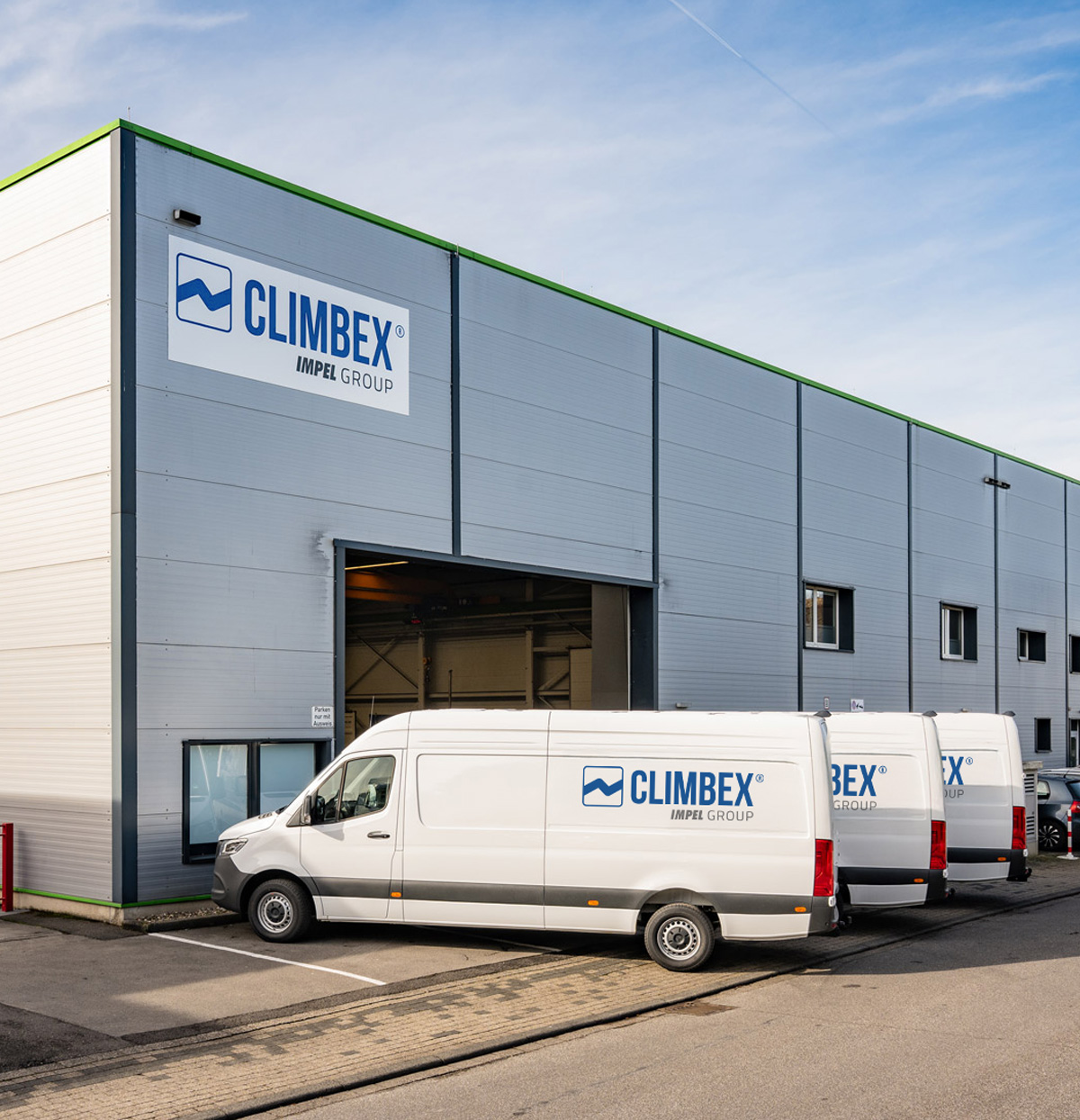 Climbex Gebäude von außen. Mehrere Firmen-Transporter stehen davor.